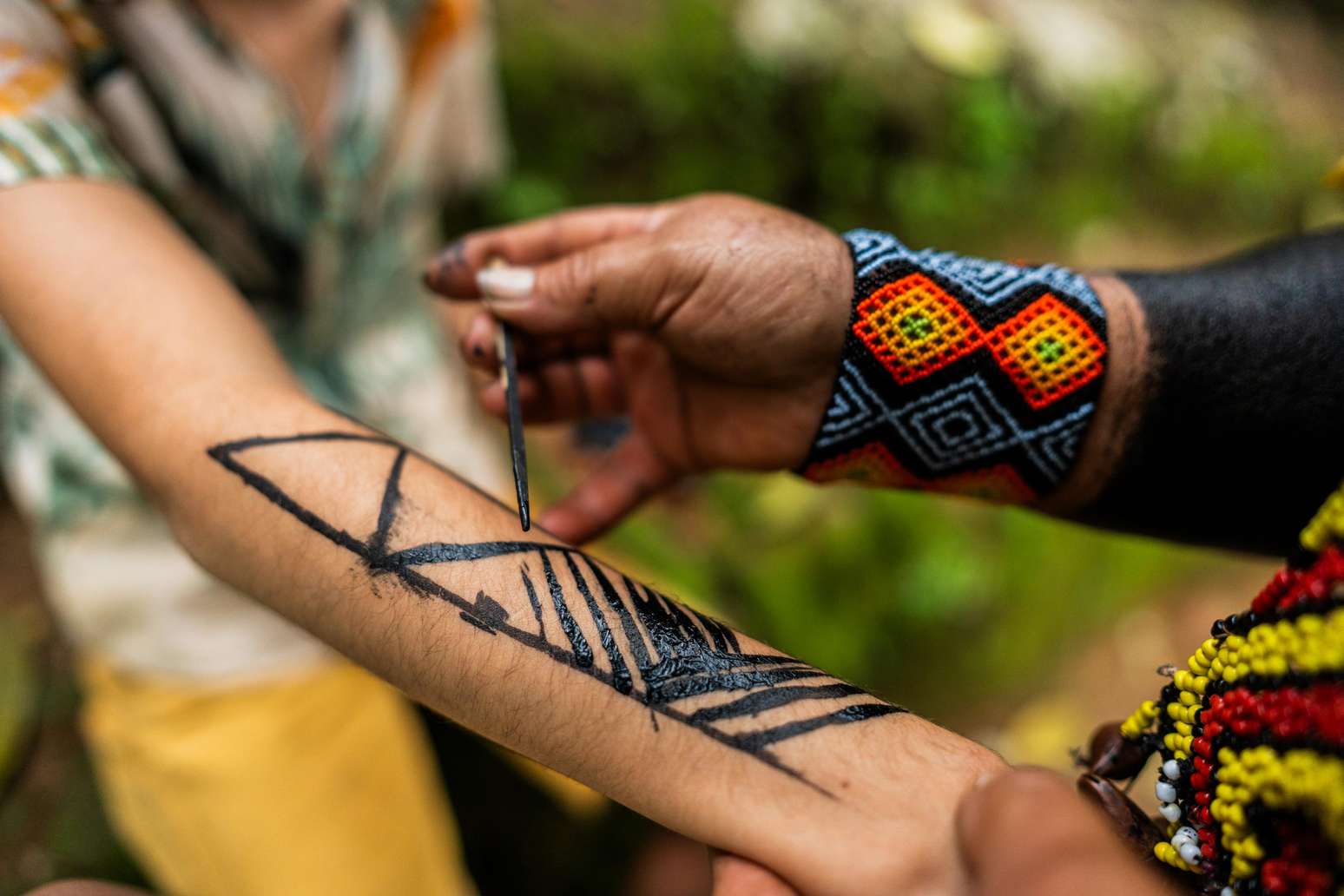 Turista fazendo pintura indígena tradicional com Jenipapo durante turnê em tribo brasileira