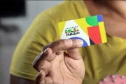 Mão segurando um cartão do Bolsa Família