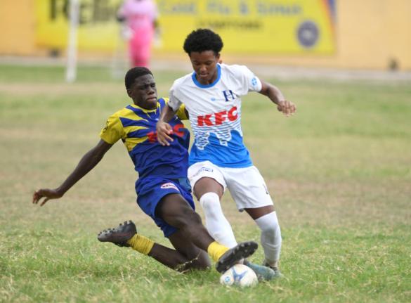 HIllel Academy’s Christian Foster (right) comes under a crunching challenge from St Mary’s College’s Dellano Nelson during their ISSA Manning Cup game at the Hillel playfield yesterday.