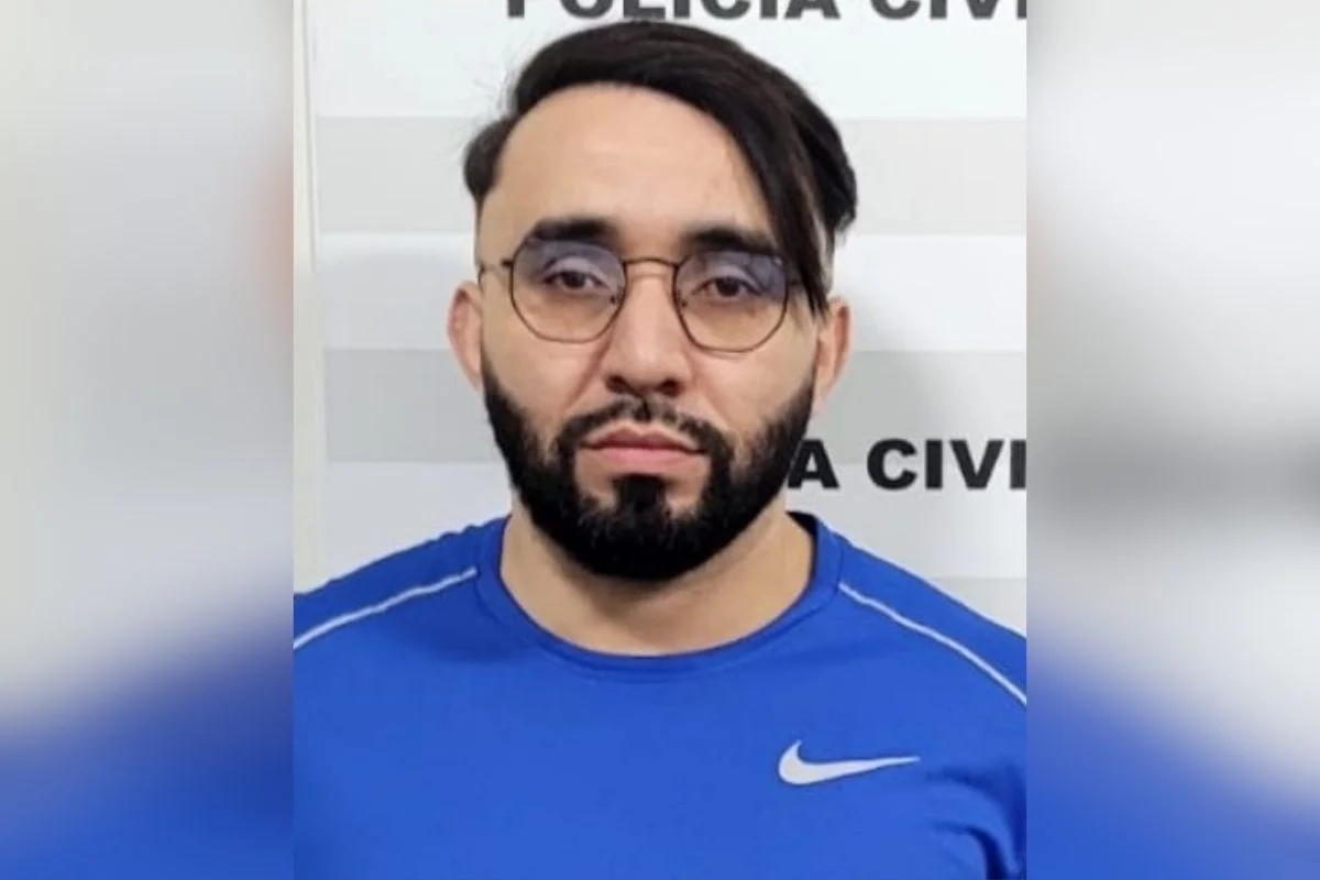 Foto colorida de homem em frente à cartaz de identificação da Polícia Civil.