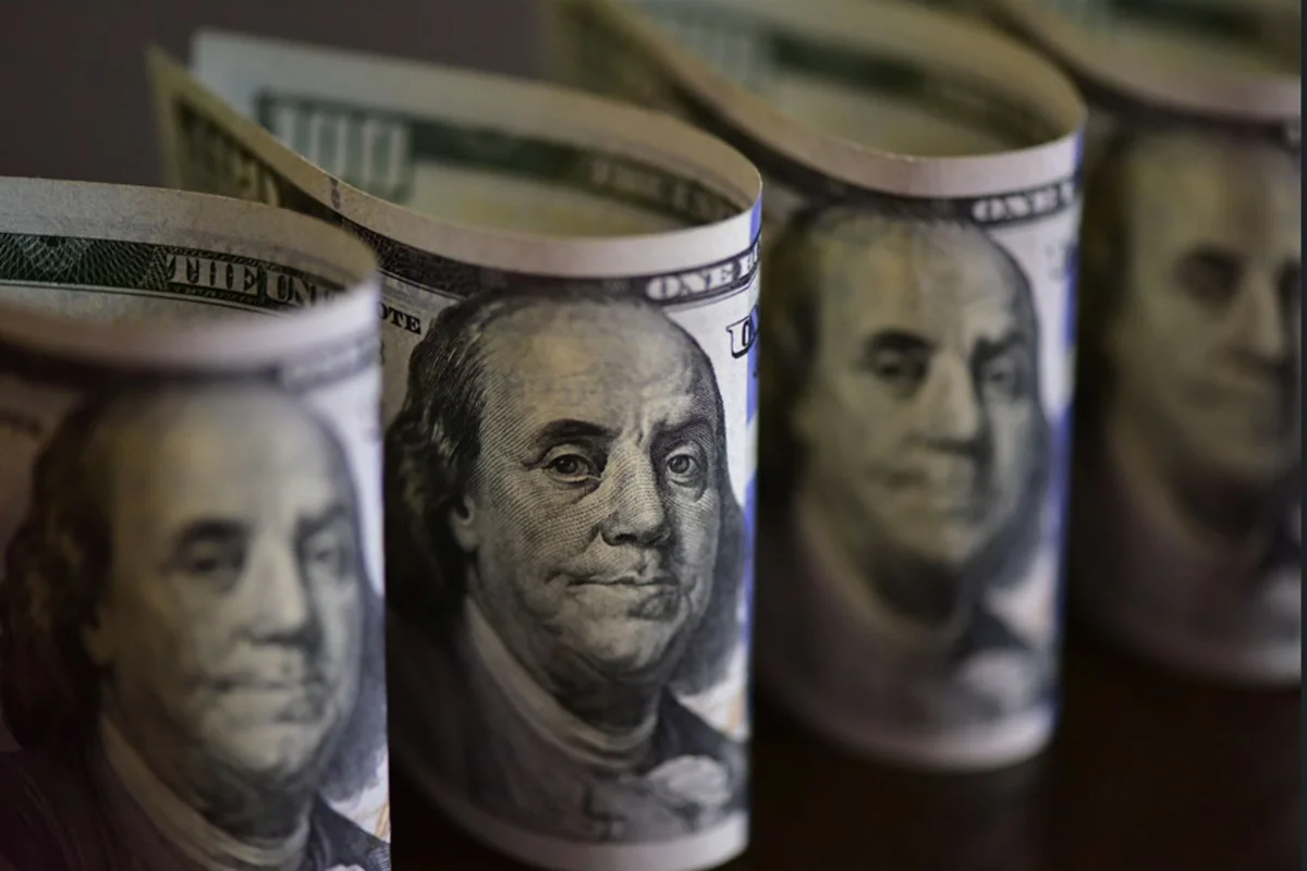 Imagem colorida de maços de notas de dólar norte-americano - Metrópoles