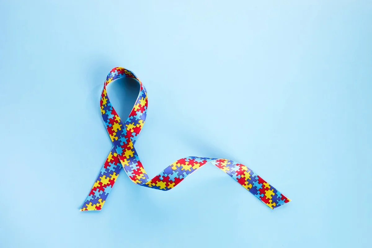 Conceito de conscientização sobre autismo com fita colorida sobre fundo azul - Autismo em mulheres: por que os sinais costumam passar despercebidos? - Metrópoles