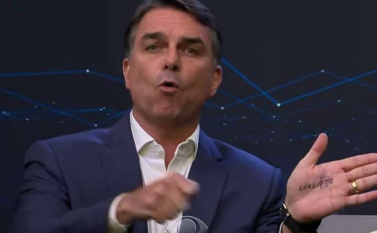 Flávio Bolsonaro mostra palavra 'corrupto' durante debate com Lula e provoca presidente
